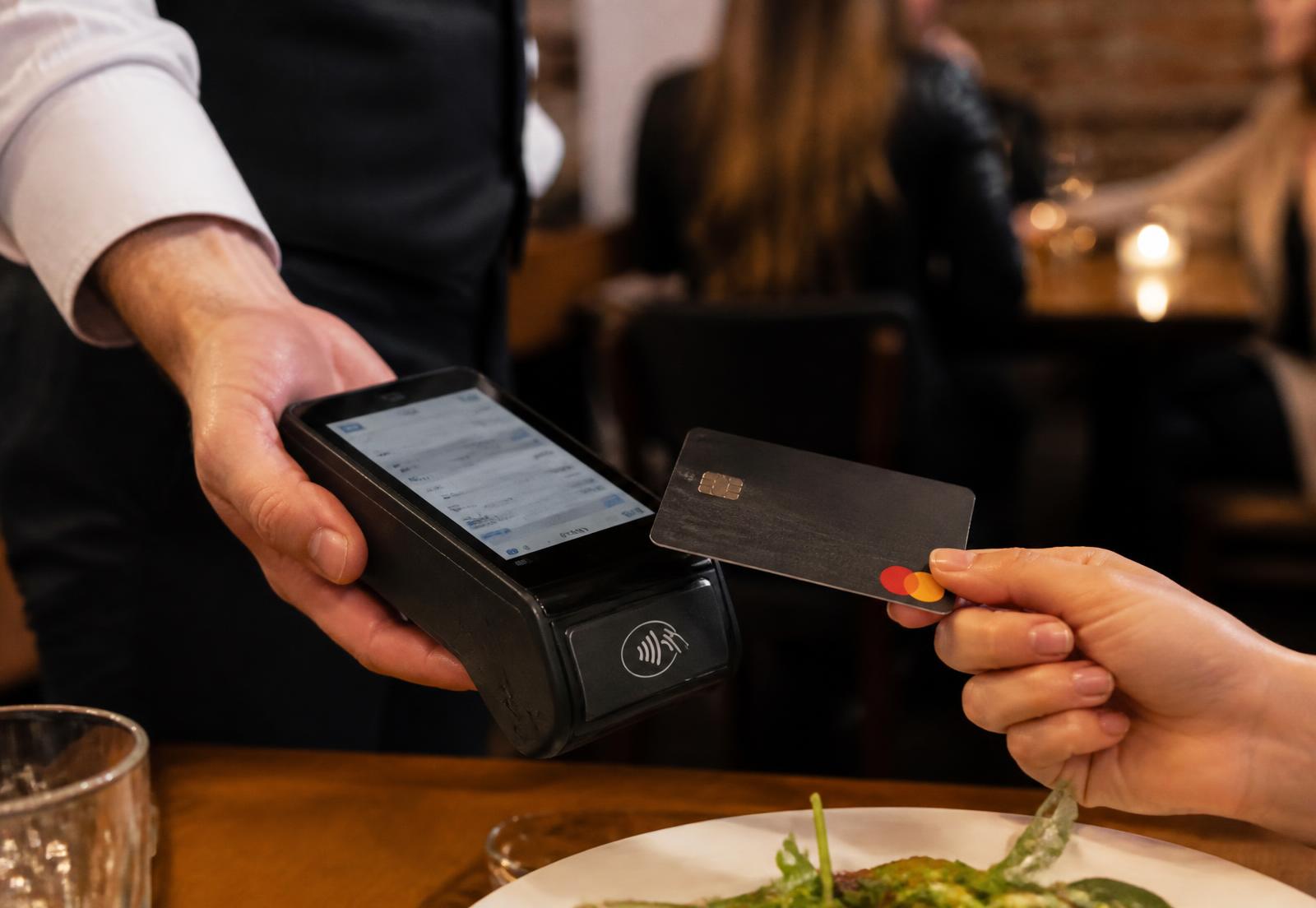 Gäst betalar med kort i Qpay HandPOS vid ett restaurangbord
